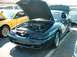1995 Ford Crown Victoria - A dark teal 1995 Ford Mustang GT is displayed with its hood open, revealing the engine, next to a yellow Mustang.