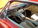 1995 Ford Crown Victoria - The interior of a classic red 1965 Ford Mustang features a wood-rimmed steering wheel and tan upholstery.