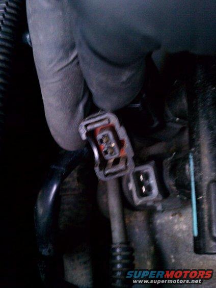 Gloved hand disconnects a red and black electrical connector with two pins