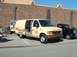 1995 Ford Crown Victoria - A beige sheriff van is parked next to a black vintage truck in front of a brick building.