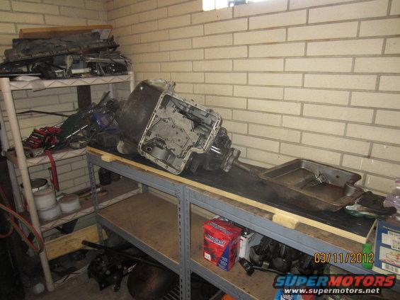 transmission and other car parts on shelves in a garage