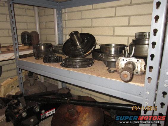 Various transmission components, including a torque converter and gears, stored on a metal shelf