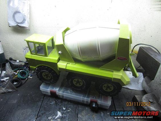 Green and white toy cement mixer truck on a clear plastic toolbox