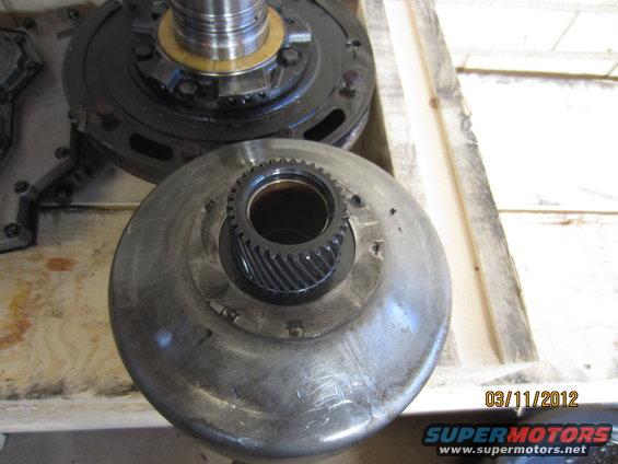 Close-up of a transmission torque converter with a gear in the center, next to a transmission pump. Date stamp 03/11/2012