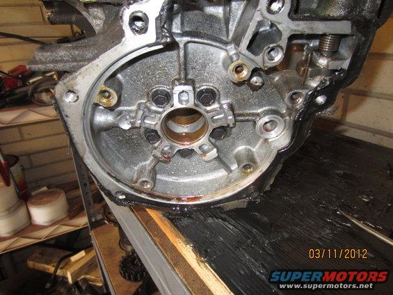 Close-up of an engine transmission housing with bolts and oil. Date stamp 03/11/2012
