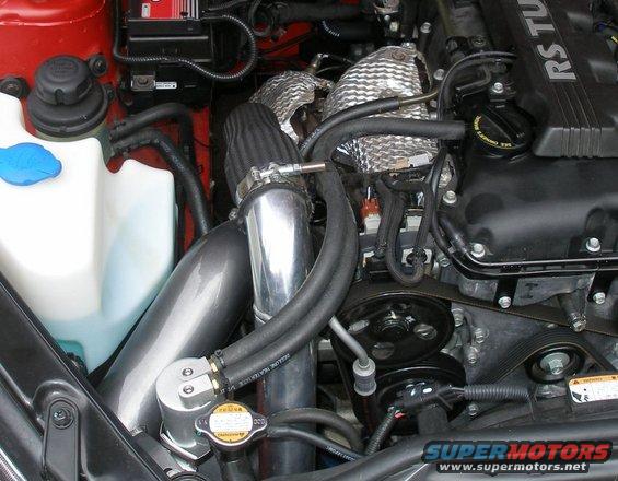Engine bay with aftermarket catch can, air intake, and heat shielding. A blue cap is visible on a white fluid reservoir