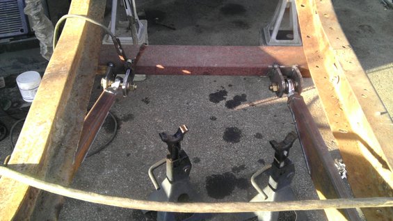 Truck frame section with suspension components attached, supported by jack stands