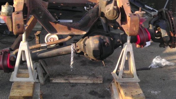 Front axle assembly with differential, brake rotors, and suspension components, supported by jack stands
