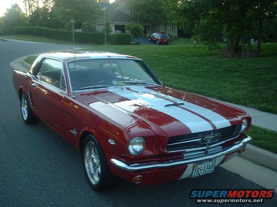 Red 1965 Ford Mustang coupe with white racing stripes parked on a suburban street