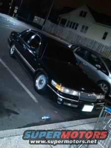Black 1994 Mercury Grand Marquis parked in a lot at night, another car next to it