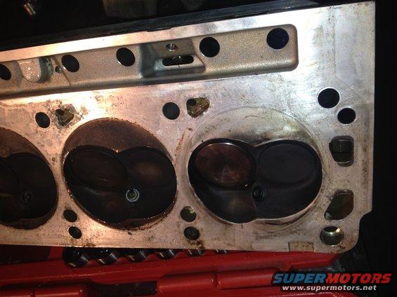 Close-up of an engine cylinder head with visible carbon buildup around the valves