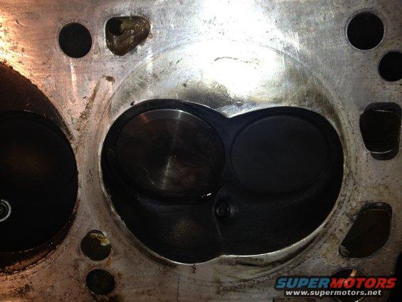 Engine cylinder head with two valve openings, showing wear and oil residue