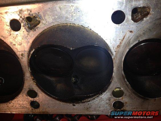 Close-up of an engine cylinder head with two large valves visible, covered in carbon buildup