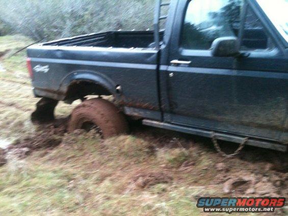 Side view of a dark 1994 Ford F-150 stuck in mud