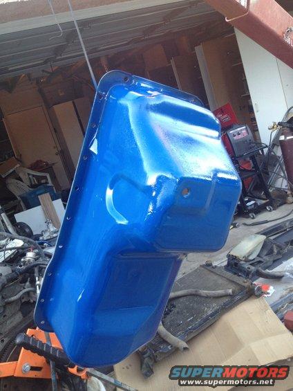 Blue painted oil pan hanging from a hoist in a garage
