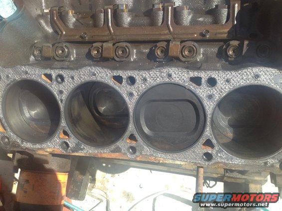 Close-up of engine block cylinders and pistons. Some pistons are visible inside the cylinders