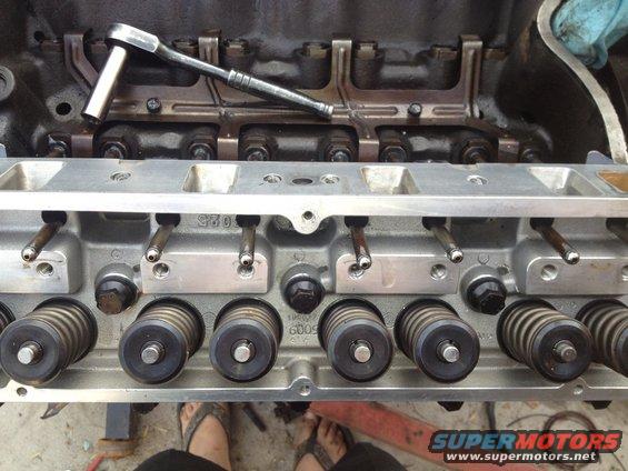 Engine cylinder head with valve springs and a ratchet on top, showing metal components and bolts