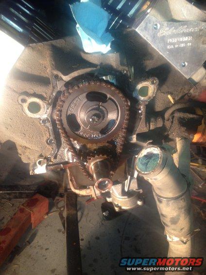 Engine timing chain and gears with a metal plate that says Edelbrock