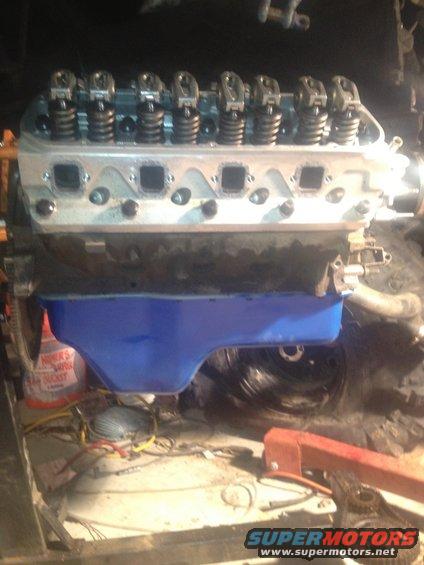 Engine block with blue oil pan and valve covers, undergoing repair