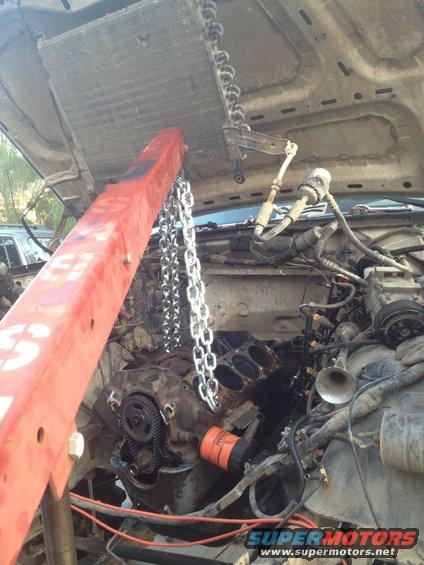 Engine being lifted out of a vehicle with a red engine hoist and chains