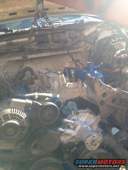 Engine components being lifted by chains, including alternator and water pump