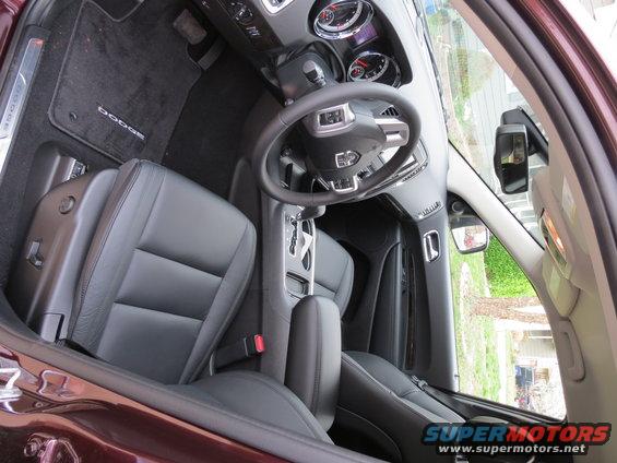 Maroon SUV interior with black leather seats, dashboard, steering wheel, and center console. Dodge floor mats visible