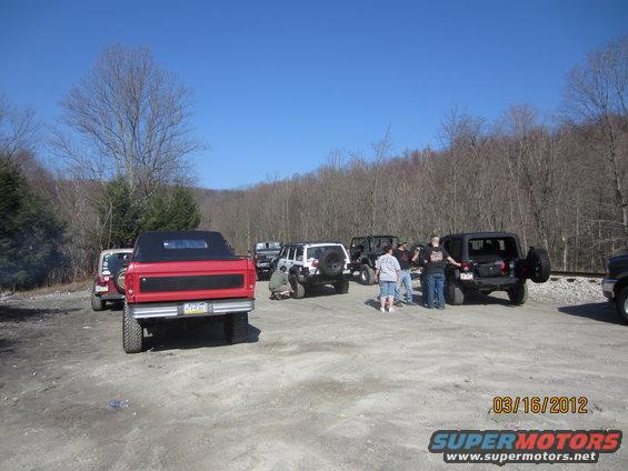 Red pickup truck with black soft top, rear view, lifted suspension, aftermarket bumper