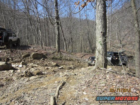 Off-road vehicles navigating a rocky, wooded trail
