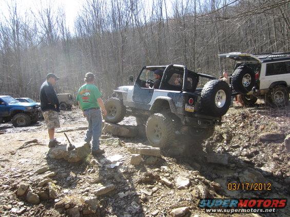 Jeep Wrangler navigating rocky terrain, rear-mounted spare tire visible