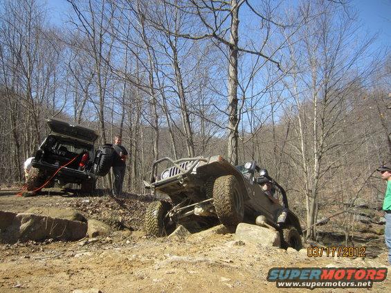 Two off-road vehicles navigating a rocky terrain, one with its rear door open