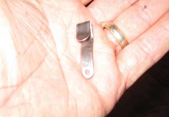 Metal clip with a hole at the end, held in a person's palm