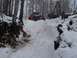 1994 Ford Bronco - A red off-road vehicle navigates a challenging snowy terrain in a forest.