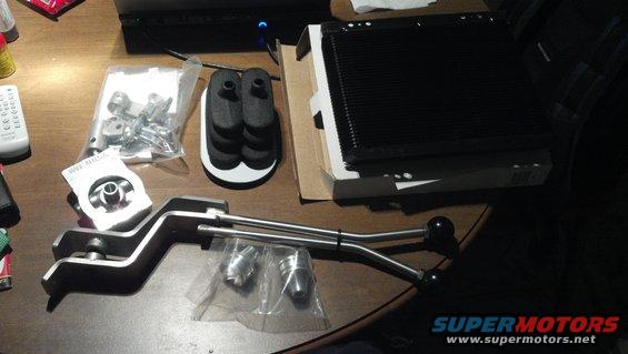Transmission shifter levers, oil filter housing, and radiator cooler parts on a wooden surface