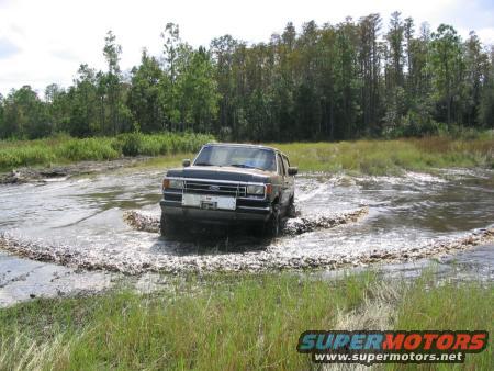 1991 Ford Bronco driving through water and mud