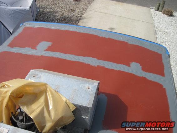 Trailer roof with red primer and gray filler patches, covered equipment