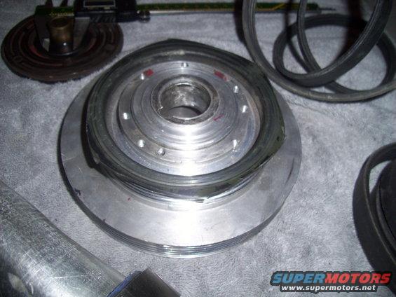 Metal pulley with a rubber belt and a caliper tool on a grey surface