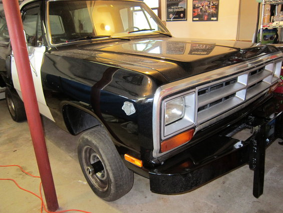 Front corner of a black and white 1987 Dodge 1500 pickup truck with a snow plow mount