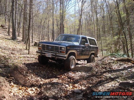 1985 Ford Bronco navigating a rocky forest trail