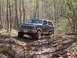 1985 Ford Bronco - This Ford Bronco navigates a rocky, wooded trail, kicking up dirt as it goes.