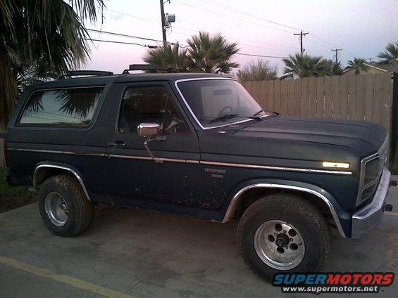 Dark blue 1985 Ford Bronco side view with chrome trim and roof rack