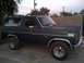 1985 Ford Bronco - This 1985 Ford Bronco features a dark blue exterior with chrome accents and a roof rack, seen from the side.