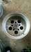 1985 Ford Bronco - A single aluminum wheel is shown from a top-down perspective, resting on a rough surface.