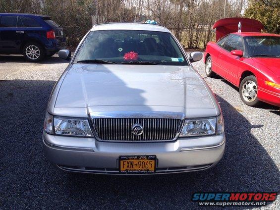 Silver 2005 Mercury Grand Marquis front view with red bow on dashboard