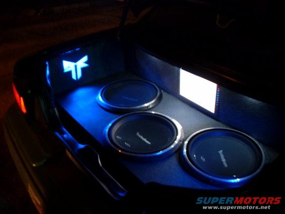 Trunk with three subwoofers and blue LED lighting, a stylized logo
