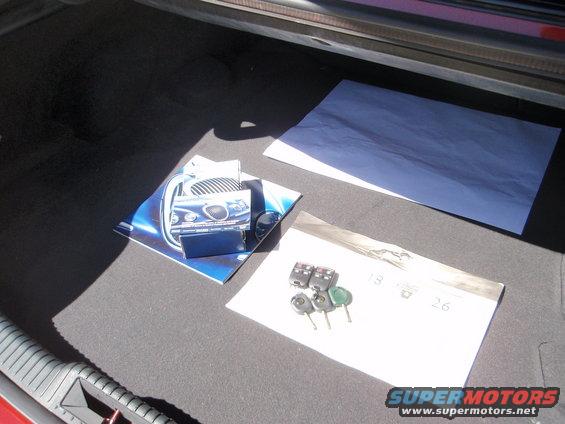 Car keys and brochures on the carpeted floor of a vehicle trunk