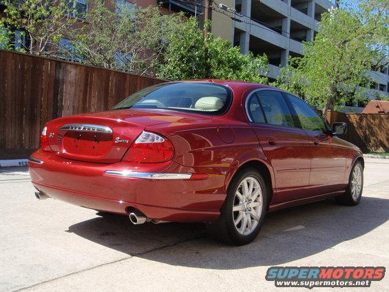 Red Jaguar S-Type sedan, rear 3/4 view. Chrome trim on rear bumper and along the side