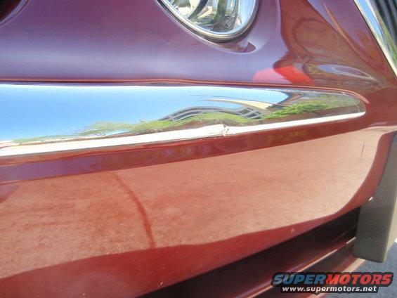 Red car front detail with chrome trim and headlight
