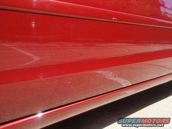 Close-up of a red car's lower door panel and rocker trim