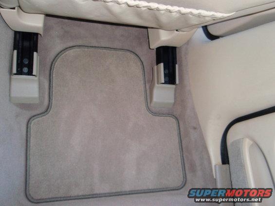 Car interior floor mat with gray carpet and dark gray piping, showing seat rails