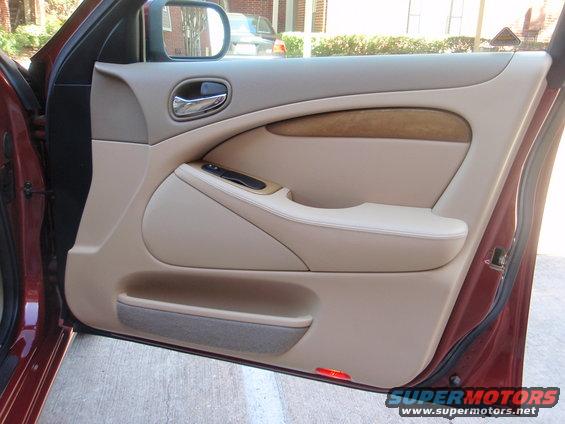 Tan interior door panel with wood trim and chrome handle. 2000 Jaguar S-Type